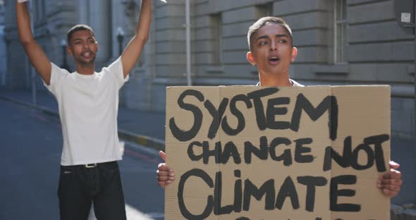 Two mixed race men on a protest march holding placards raising hands and shouting