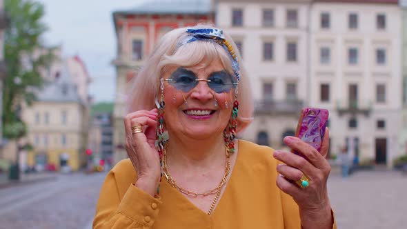 Senior Grandmother Woman Tourist with Smartphone Smiling Listening Music in App Wearing Earphones