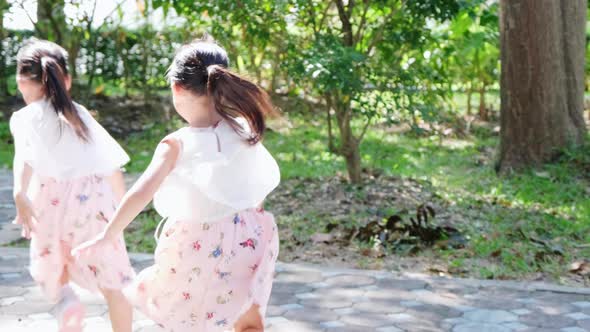 Active little sisters are running in the outdoor playground in the park.