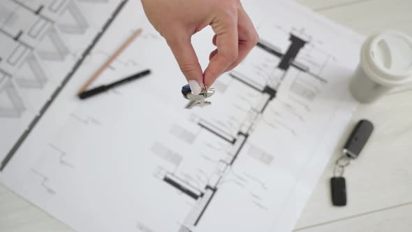 The Hand Holds the Keys To the House. Against the Background Architectural Plan of the Apartment 