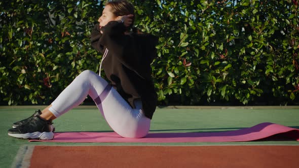 Young Woman Lying on Mat and Pumping Press in the Park