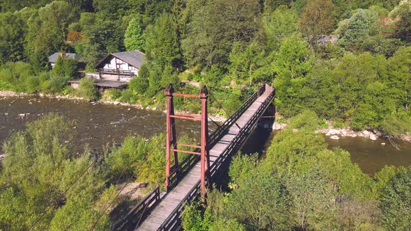 Aerial View From Old Wooden Suspension Bridge Over a Mountain River. Girl Standing on a Wooden