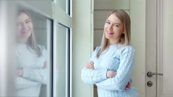 Attractive Smiling European Girl Near Window with Crossed Hands Medium Shot