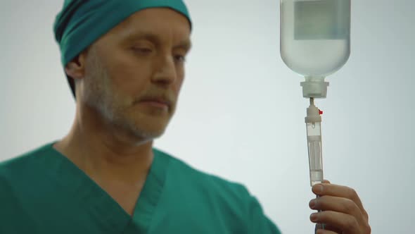 Male Physician Looking at Medicine Dropping in IV Equipment, Doctor Nodding