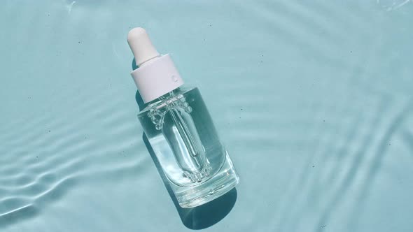 Glass Cosmetic Bottle with Pipette Lies on the Surface of the Water