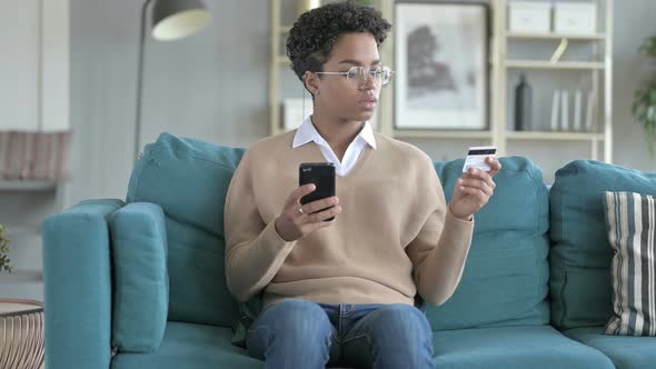 Young African Using Credit Card on Cell-phone