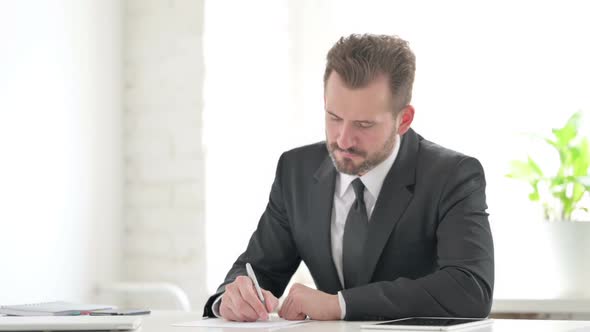 Young Businessman Having Disappointment While Writing on Paper