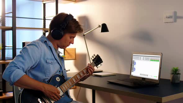 Man Playing Guitar and Recording Music at Home