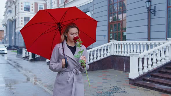 Blond Girl Goes Down Street Under Red Umbrella