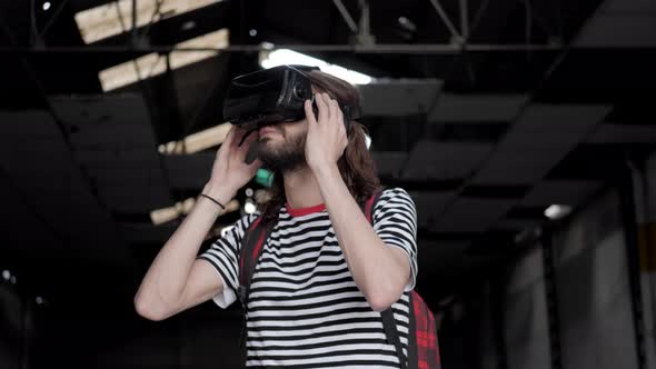 Young man wearing virtual reality glasses exploring abandoned warehouse