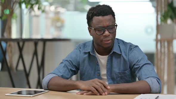 Upset Young African Man Worried While Sitting in Modern Office