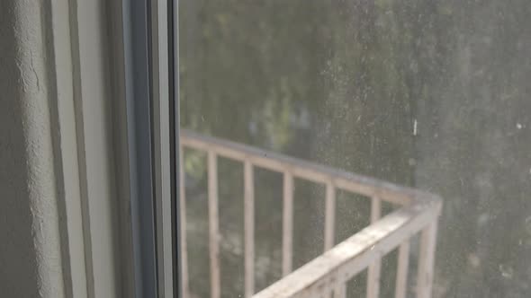 Macro shot of dirt on window that overlooks the railing of a balcony. Home interior.