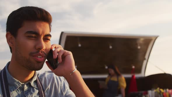 Young man talking on the phone by food truck