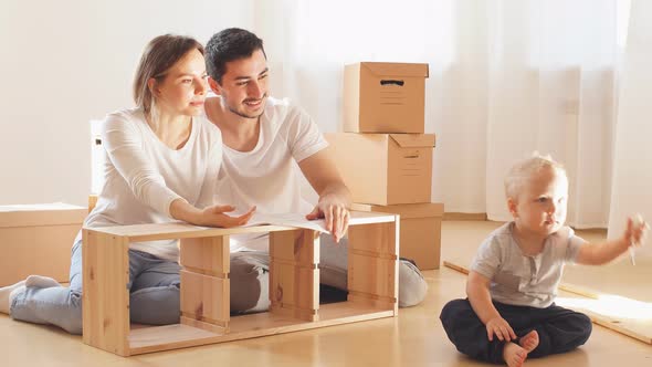 Family Together at Living Room of New Apartment Assembling Furniture