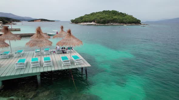 Aerial View of Empty Sunbeds Under Thatched Umbrellas on a Pier in Turquoise Sea