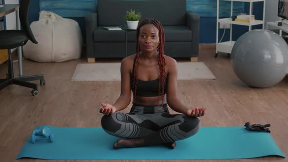Portrait of Black Woman Sitting in Lotus Position on Floor Doing Morning Breathing Workout