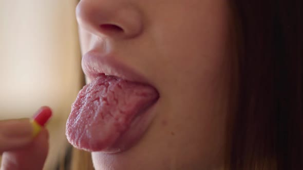 Female Hand Putting Pill on Her Tongue