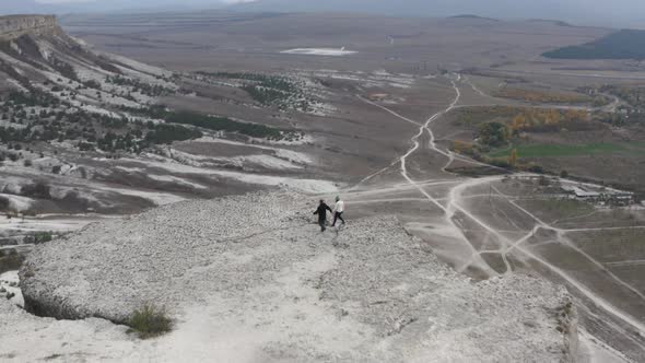 Active Couple Walking on Peak Precipice of White Cliff at Natural Hilly Terrain