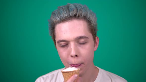 Young Happy Man with Blue Hair Eating Ice Cream in Waffle Cup Looking at Camera