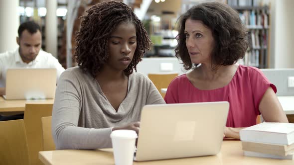 Thoughtful Women Discussing New Project at Library