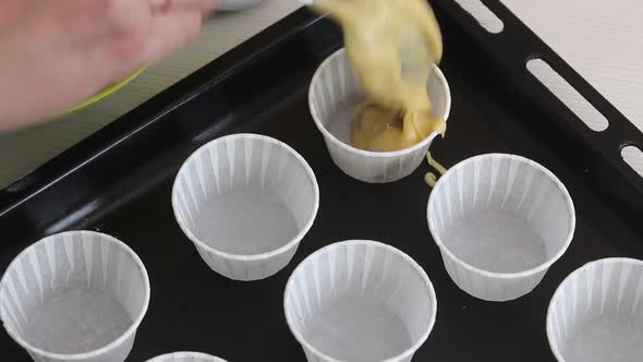 A Woman Puts The Dough Into Muffin Tins On A Baking Sheet.