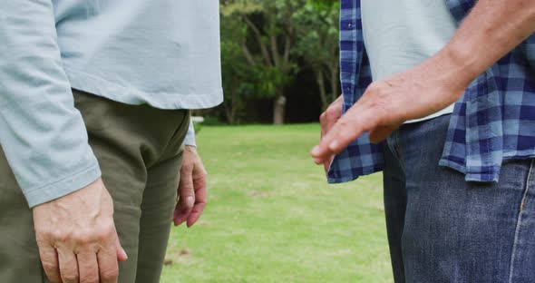 Animation of midsection of caucasian female and male senior friends holding hands in garden