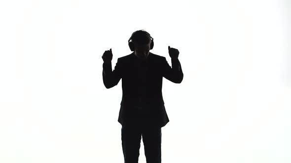 Silhouette of a Young Man Puts on Headphones and Dances To the Music