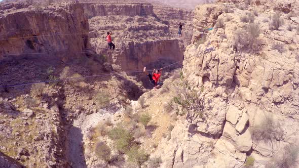 Aerial view of a man balancing while tightrope walking and slacklining across a canyon.