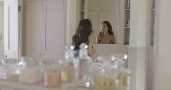 Woman looking into mirror and applying make-up