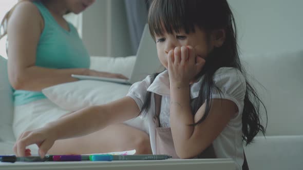 Home study concept : A Beautiful single Asian mother teaching her daughter to read, write and drawin