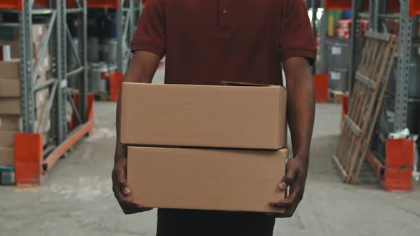 Unrecognizable Man Carrying Boxes in Warehouse