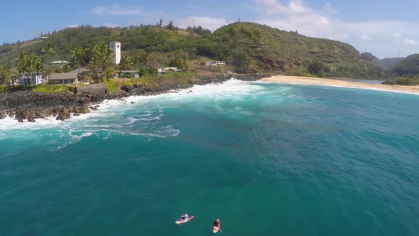 Aerial view of two men sup stand-up paddleboard surfing in Hawaii.