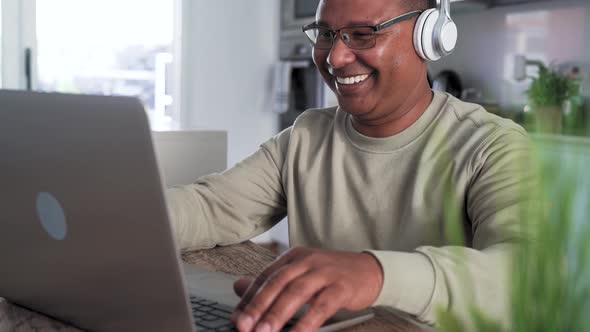 Happy senior man having fun doing video call using laptop at home