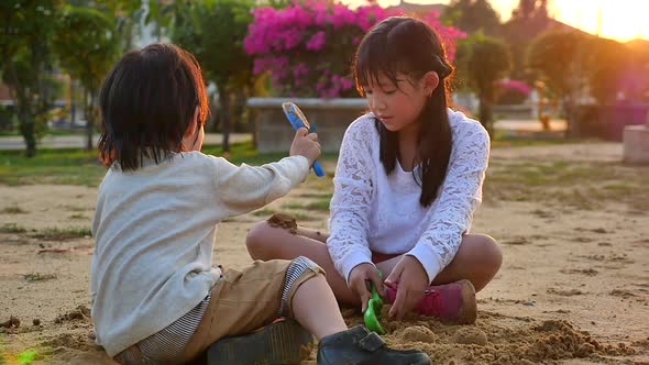 Asian Children Playing Sand In Playground Under Sunset