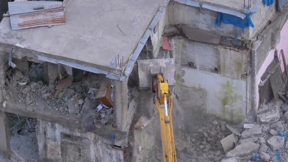 Destroying Old Concrete House Using Mechanical Arm of Bulldozer on Construction Site alt