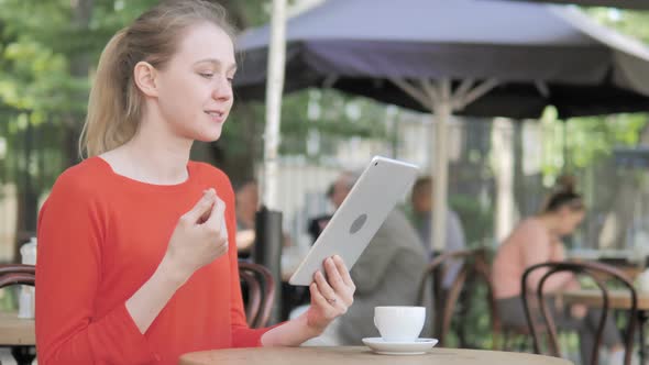 Online Video Chat on Tablet by Young Woman, Sitting in Cafe Terrace