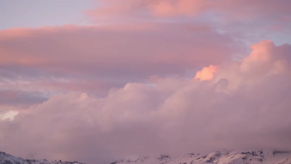 Time lapse of pink clouds over mountain top at sunset