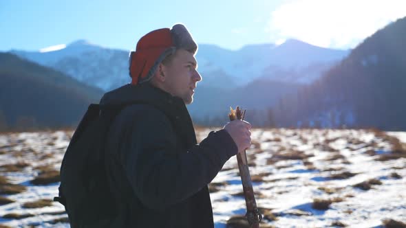 Side View of Young Hiker Going Nordic Walking with Sticks on Snowy Trail in Field at Mountain