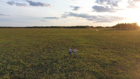 The Mother and Boy Run with a Kite on a Green Field