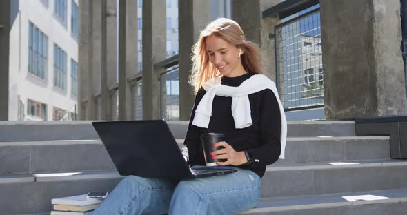 Young Woman in Casual Clothes which Sitting on Steps of City Building, Working on Laptop