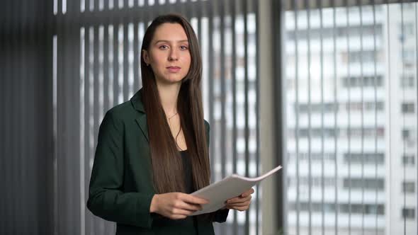 Young woman, office worker looks confidently with a smile at the camera