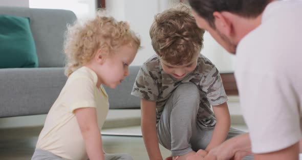 Close Up of a Little Boy and a Little Girl and Their Father are Drawing with Pencils on the White