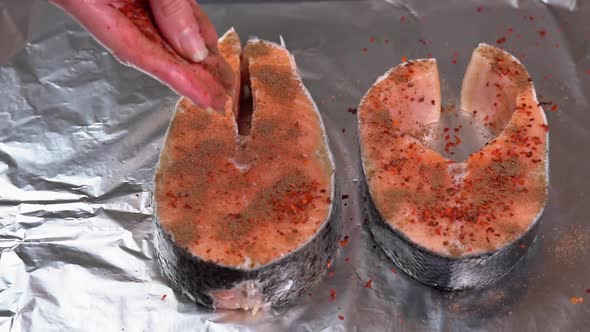 Seasoning salmon steak. Chef adding spices on raw salmon steak before baking. Raw salmon