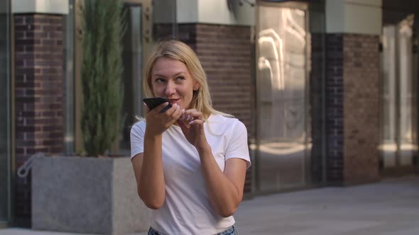 Portrait of Pretty Young Woman Talking on Her Smartphone on Speakerphone or Records a Voice Message