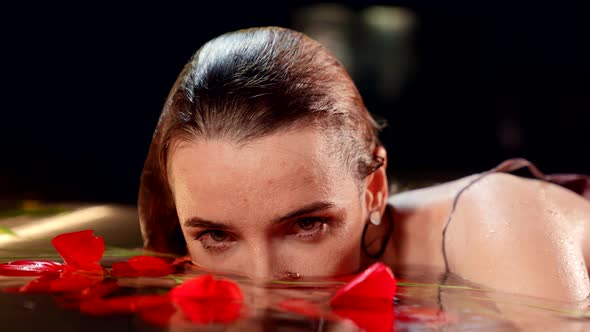 Fascinating Woman with Wet Hair is Lying in Water of Fabulous Lake with Red Flowers Closeup Portrait