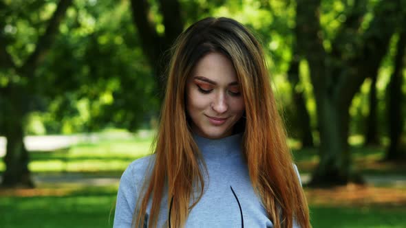 Portrait of Attractive Smiling Modern Woman with Red Hair Puts on Glasses and Looking at Camera