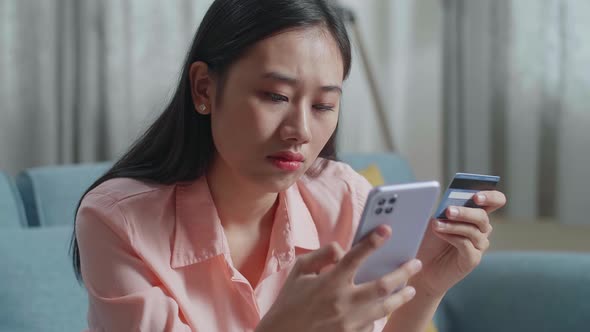 Close Up Of Asian Woman Holding Credit Card And Smartphone Shaking His Head Due To Unable Pay Money