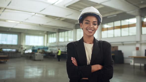 Portrait of Successful African American Woman in Helmet and Suit Standing with Arms Crossed in Big