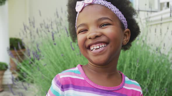 Portrait of smiling african american girl looking at camera in garden