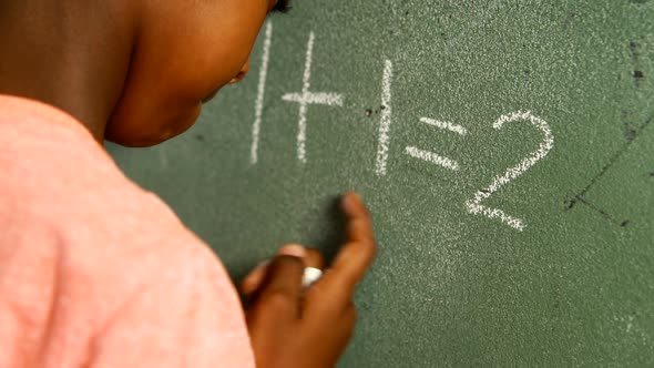 Schoolboy doing mathematics on chalkboard in classroom 4k